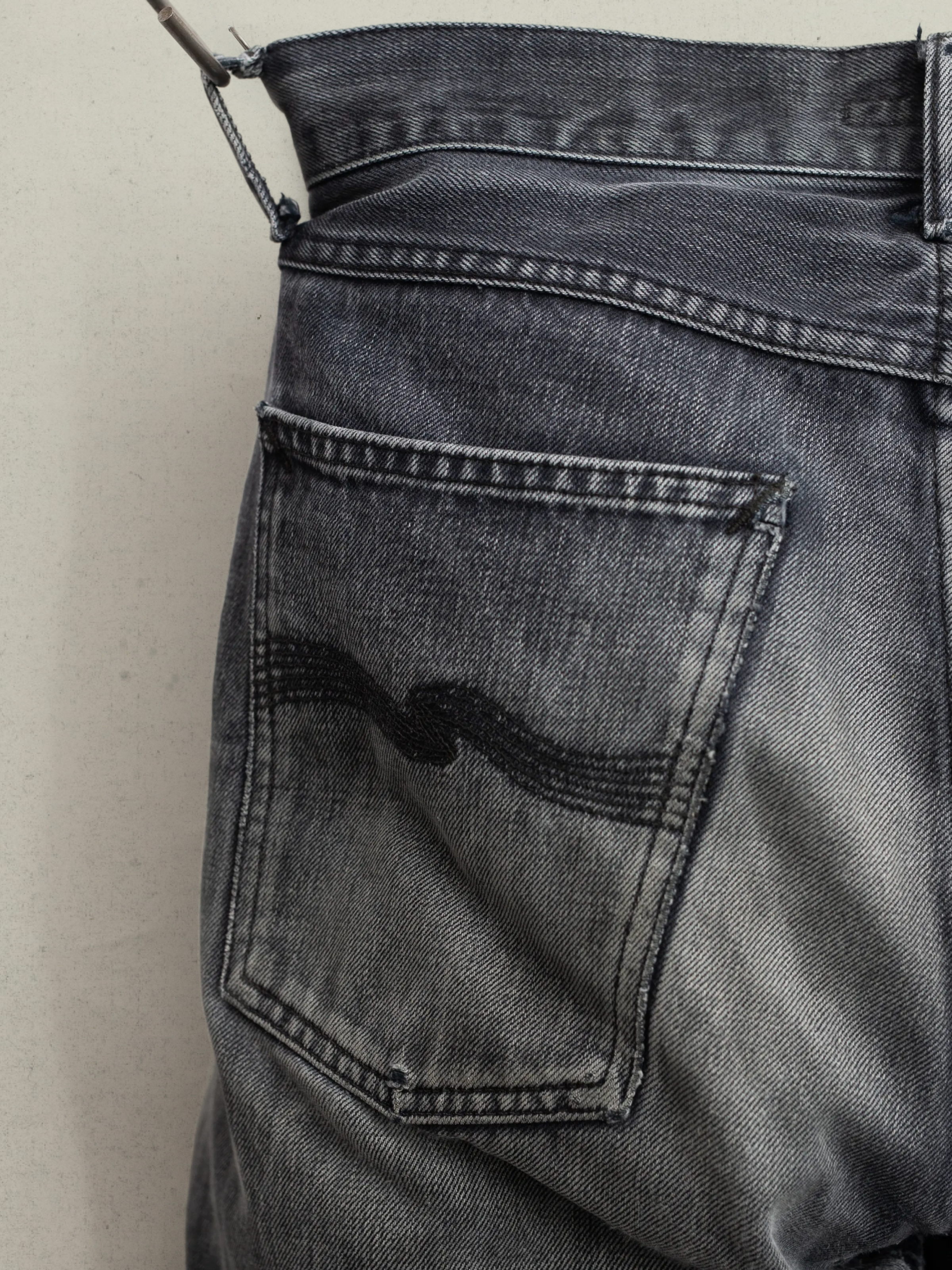 Nudie Jeans Gritty Jackson Dry Onyx Selvage, close-up of the back pocket and black selvedge denim texture.