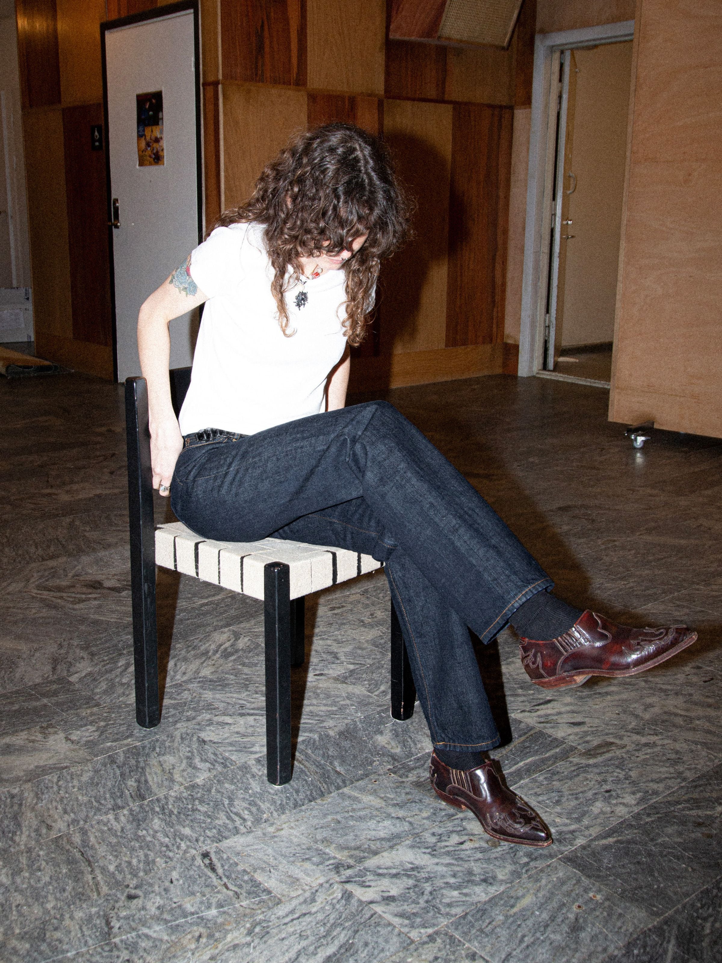 Nudie Jeans Sharp Charlie Blue One Wash, women's regular fit jeans in dark blue organic cotton, worn sitting on a chair.