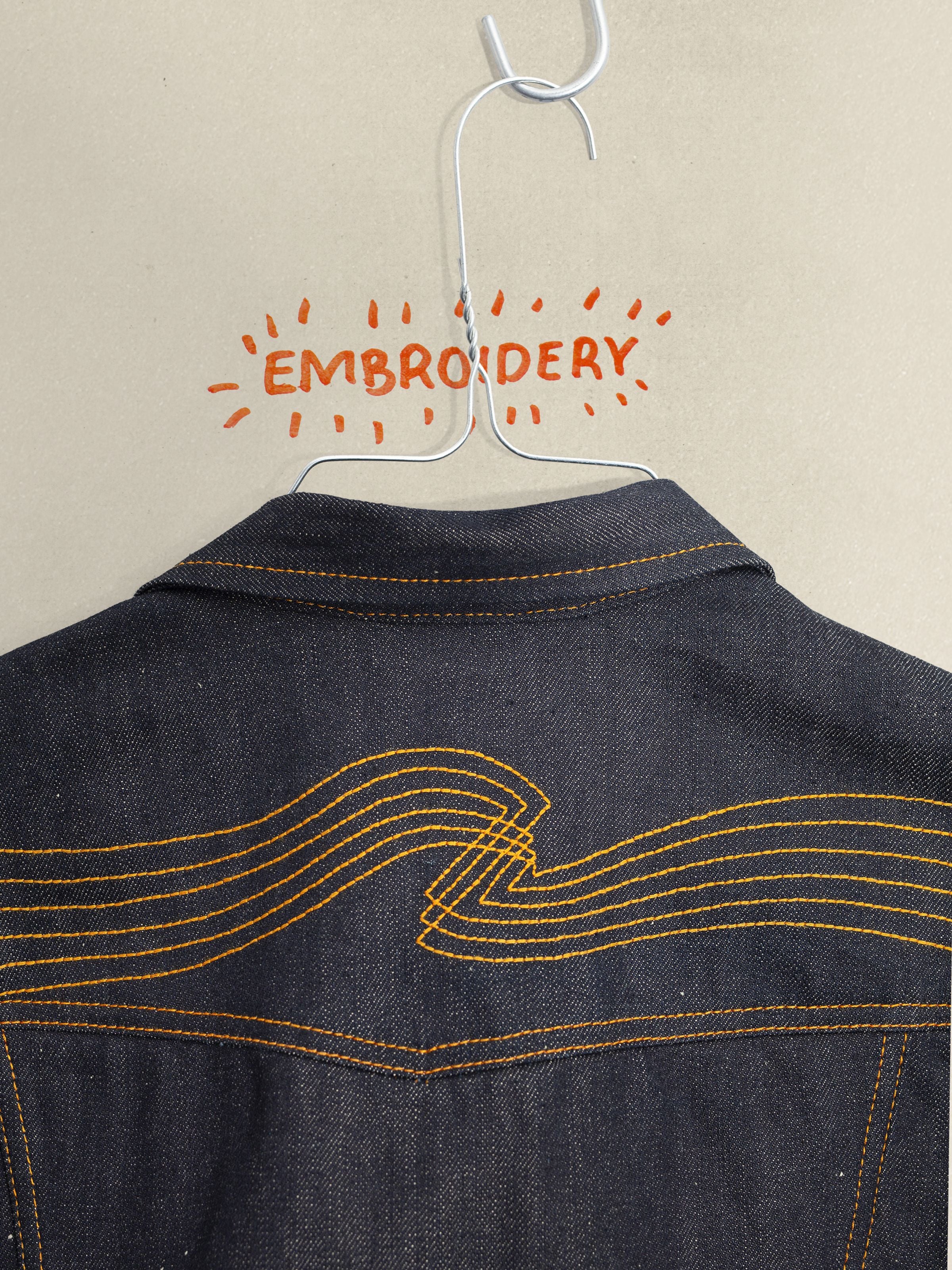 Nudie Jeans Conny Denim Jacket Dry Selvage, Nahaufnahme der Rückenpassen-Stickerei und der starren Selvedge-Denim-Textur.