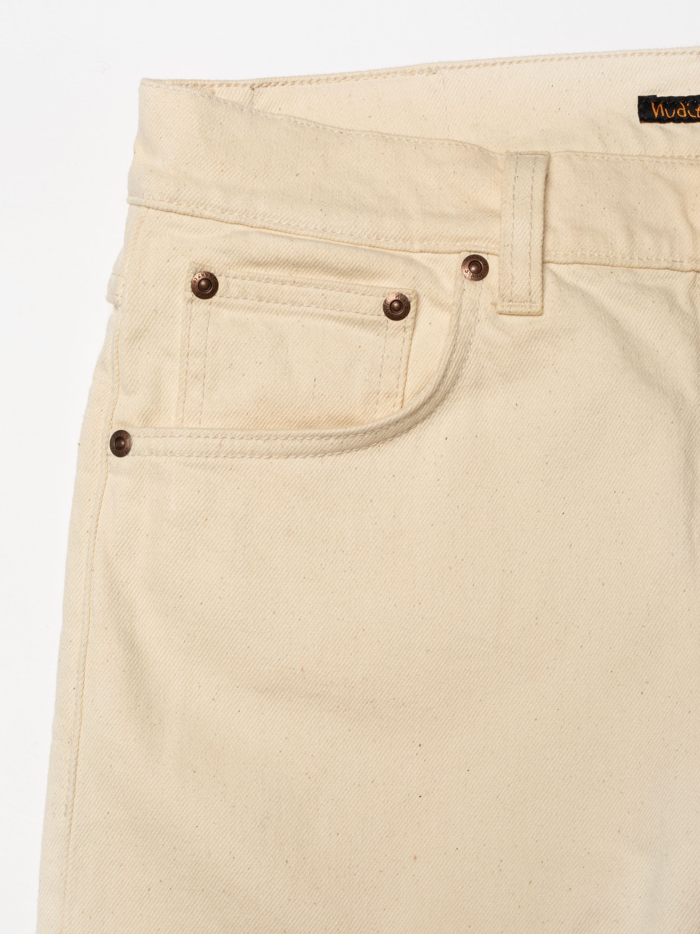 Nudie Jeans Lean Dean Ivory, a close-up of the front pocket and copper rivets on ivory organic cotton stretch denim.