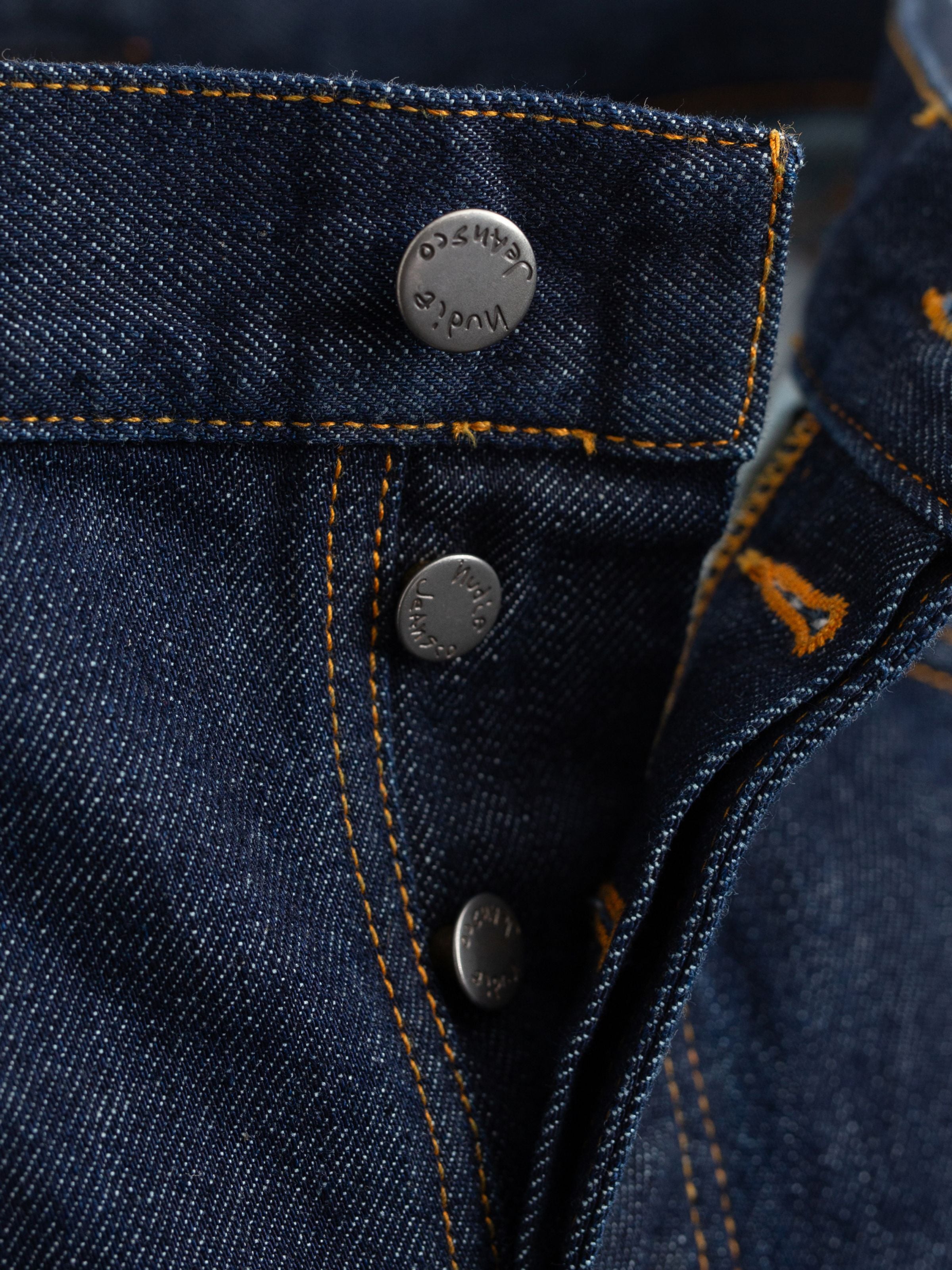 Nudie Jeans Steady Eddie II Dusk Selvage One Wash, close-up of the antique silver button fly and orange contrast stitching.