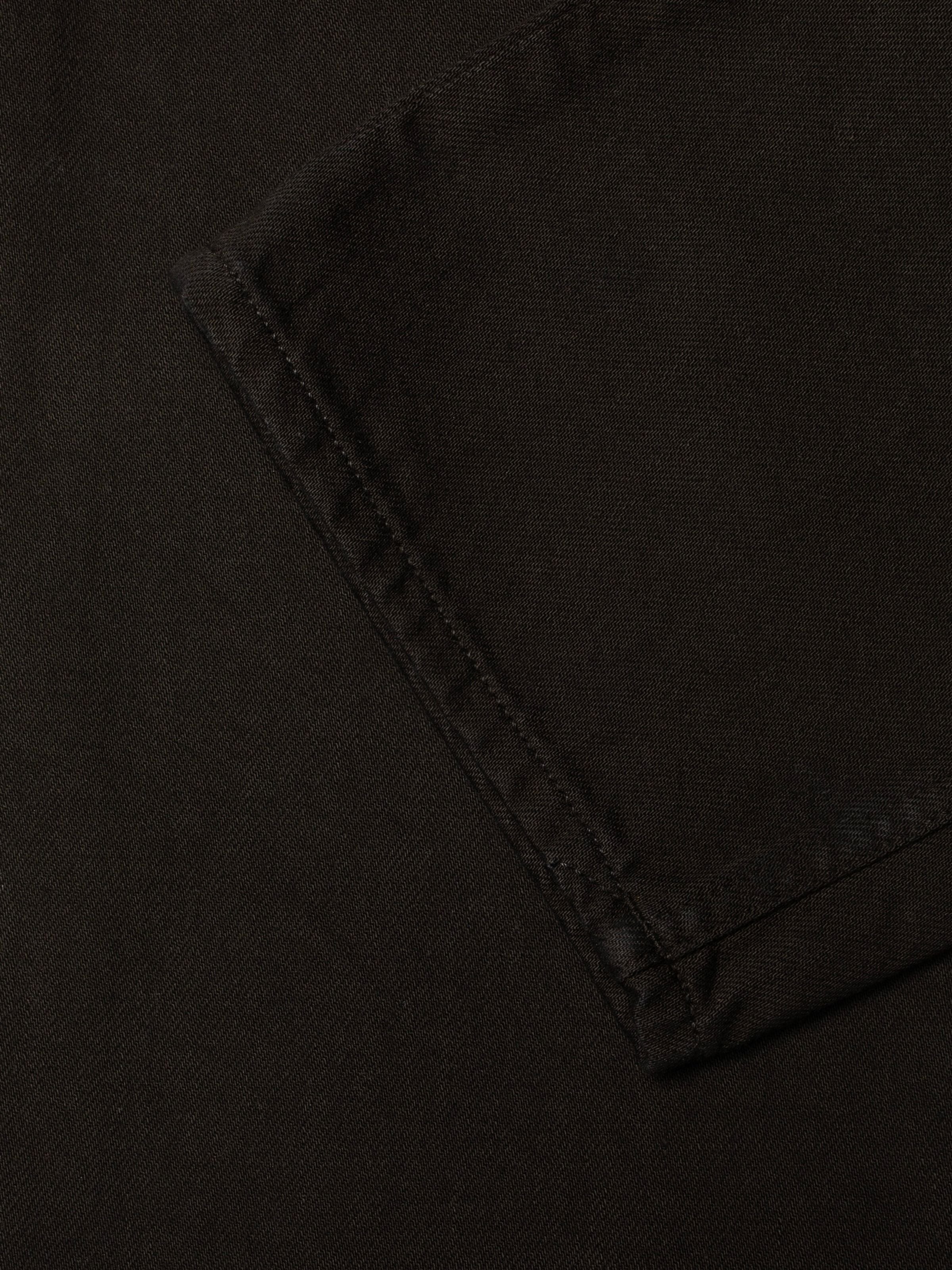 Nudie Jeans Rad Rufus Deep Black, close-up of the leg opening hem showing the rigid organic cotton denim texture.